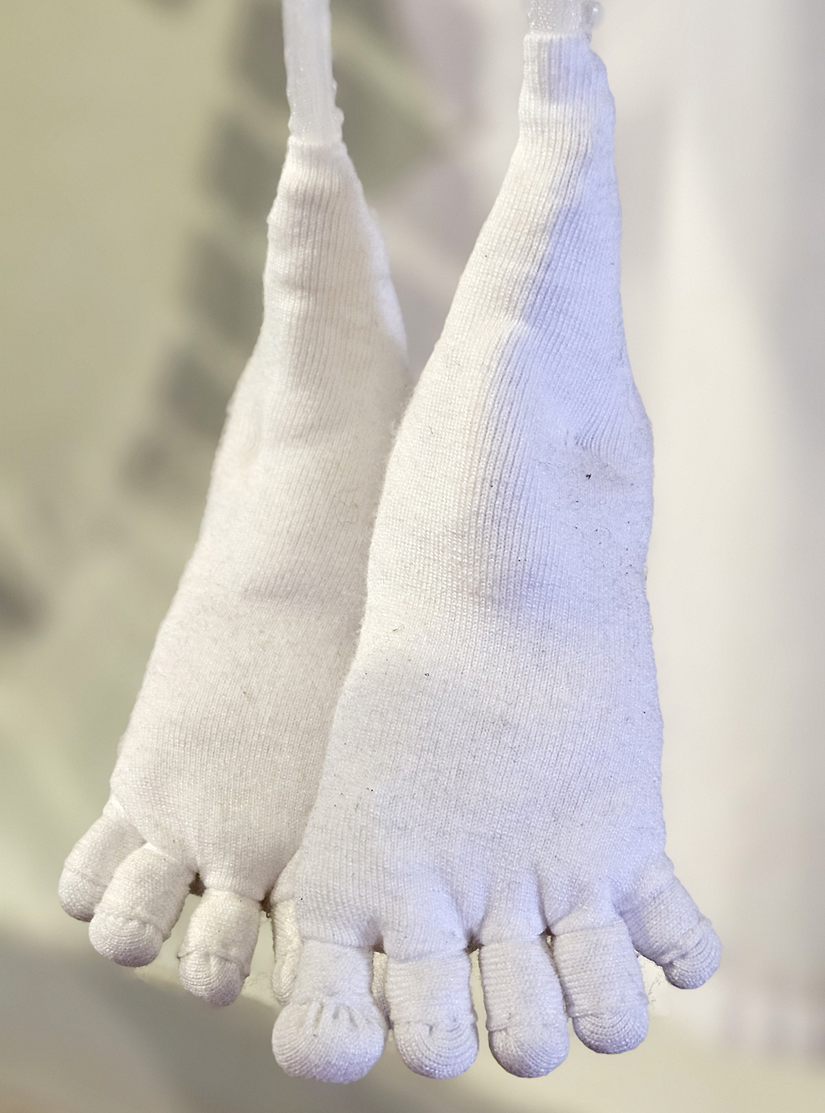 White baby feet made of fabric hanging in the air.