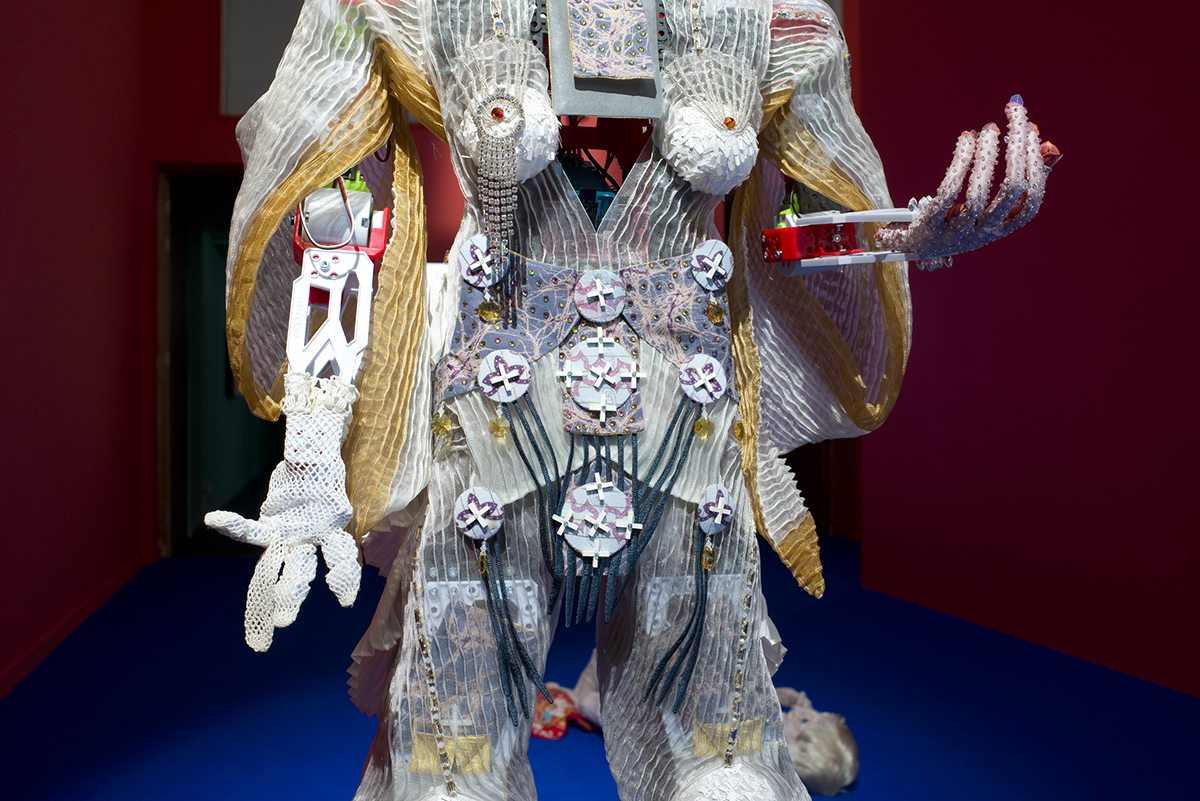 The torso of a care robot, adorned with rhinestones and a surface constructed from satin ribbon.